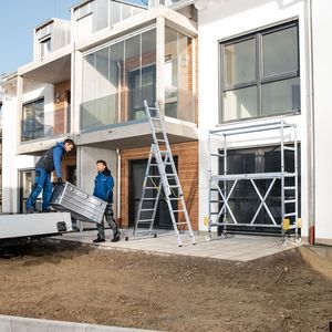 Zwei Handwerker arbeiten mit Gerüsten, Leitern und Kisten von Zarges.