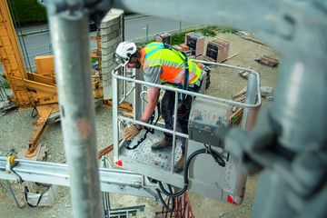 Ein Industriekletterer steht in einer Arbeitsbühne gesichert durch die ZARGES FallProtection Ausrüstung